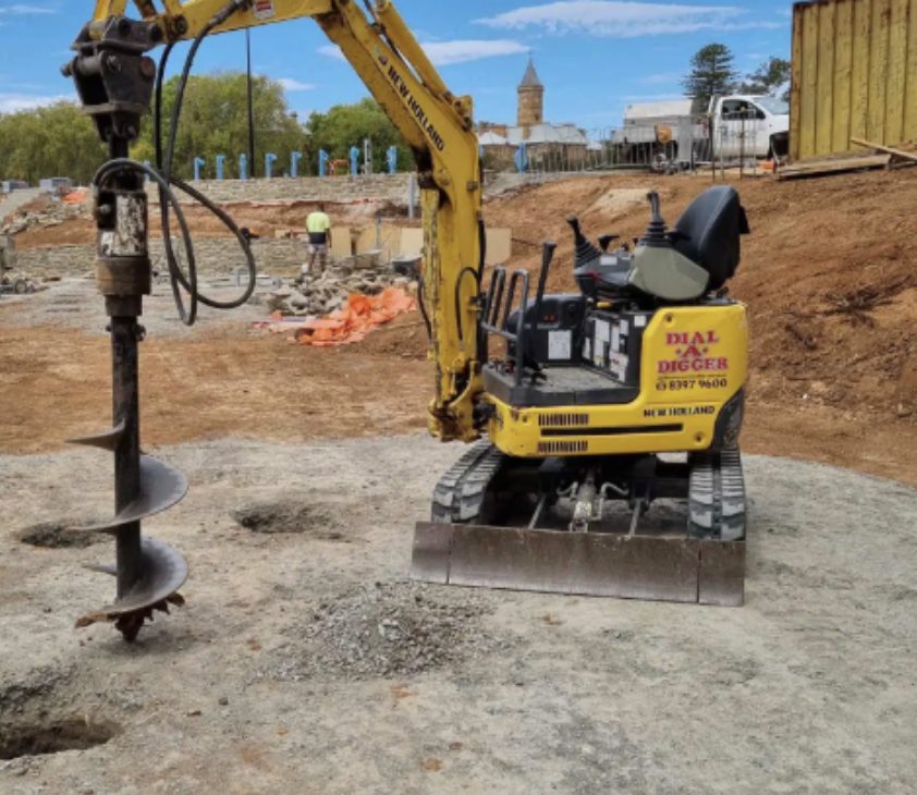 Mini excavator with auger on a Coastline Walls and Excavations site